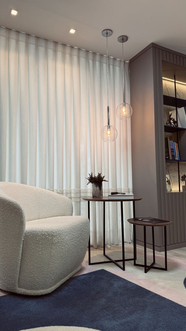 Canto de espera com poltrona e cortinas claras